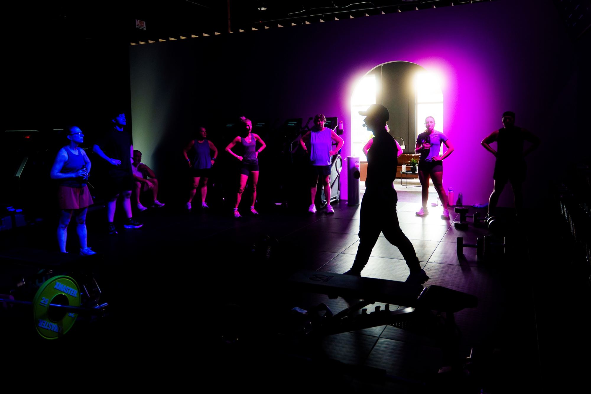 A DRFT coach leading a group class under purple light